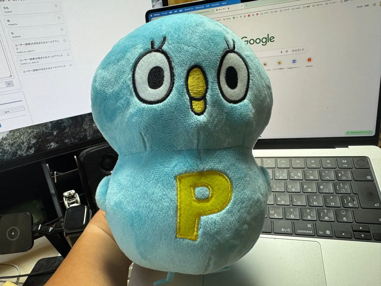 長嶺圭一郎が手に持っている、水色で胸に黄色いPの文字が入ったペライチのキャラクター「Pちゃん」のぬいぐるみ